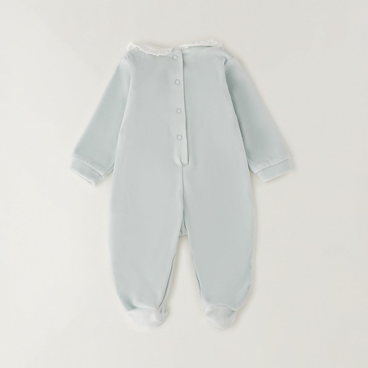 Dettaglio tutina neonata verde menta in ciniglia con colletto bianco e lavorazione smock geometrica