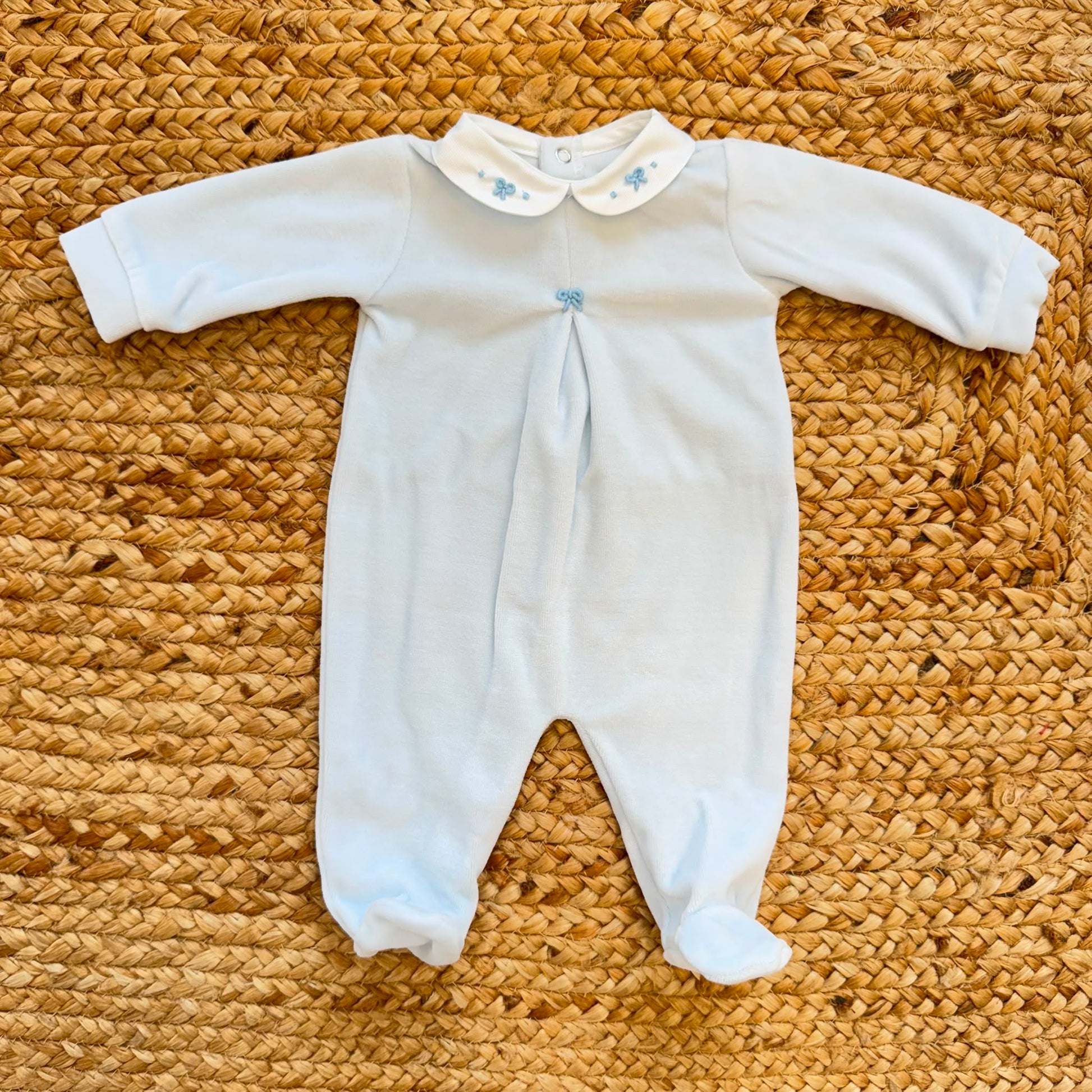 Tutina neonato in ciniglia color cielo con colletto bianco ricamato.