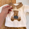 dettaglio maglia tutina neonato con applicazione orsetto e fiocco beige