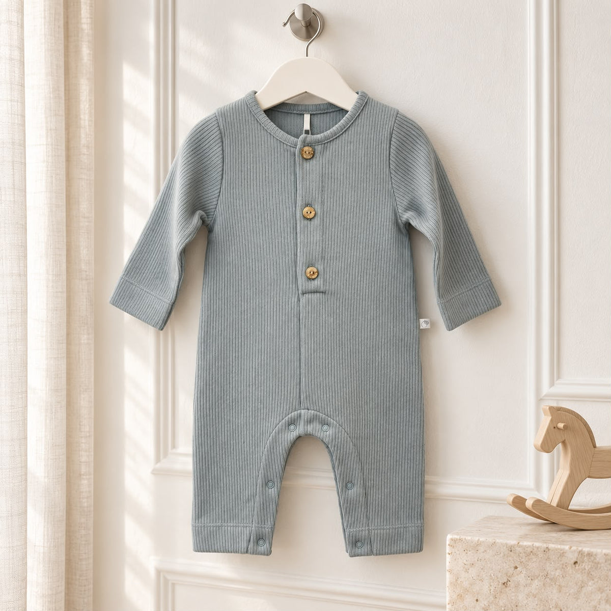 Tutina neonato in cotone 100% azzurro polvere a costine, con maniche lunghe, bottoncini frontali e apertura con automatici nell'interno gamba.