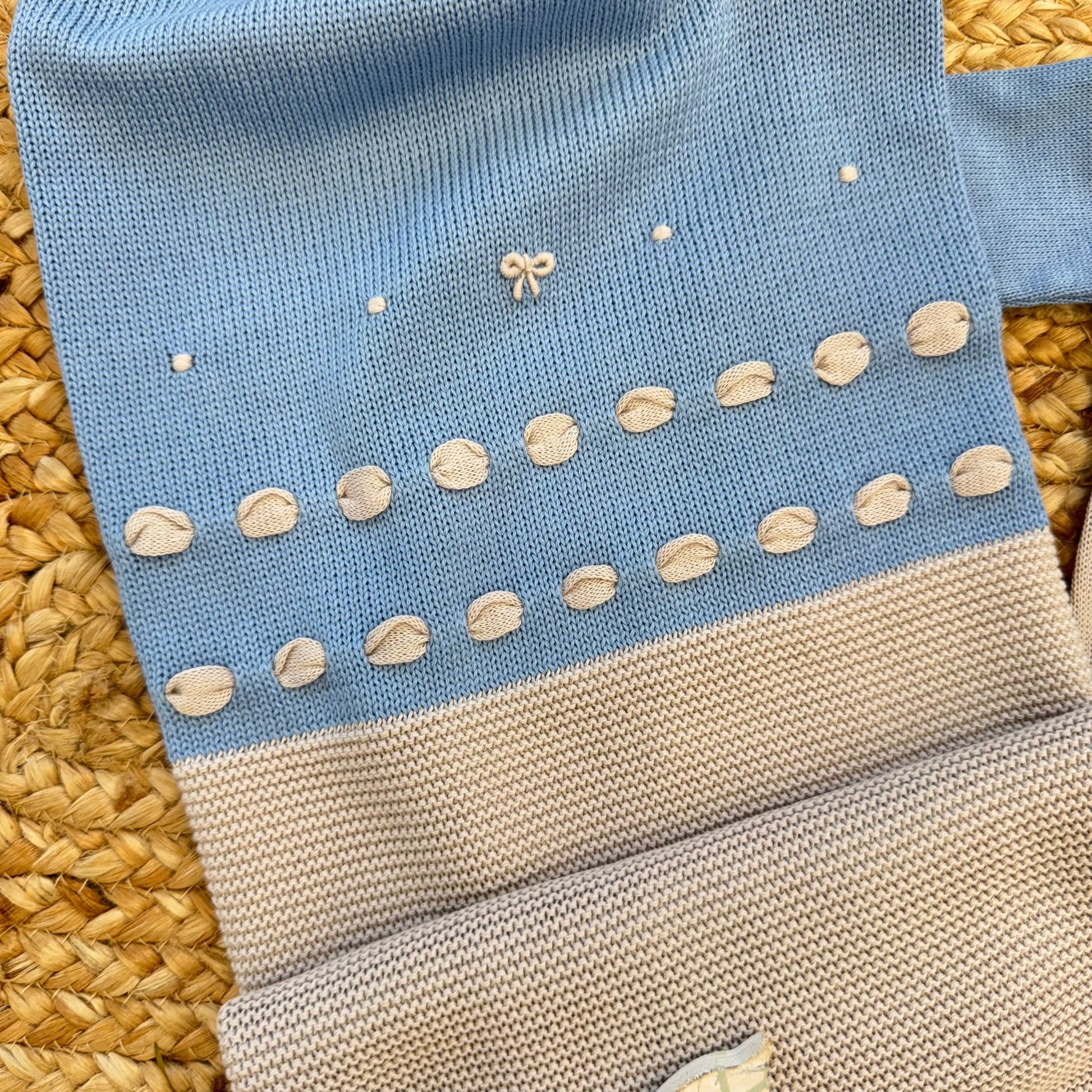 Dettaglio ricami decorativi su tutina neonato in 100% filo di cotone azzurro