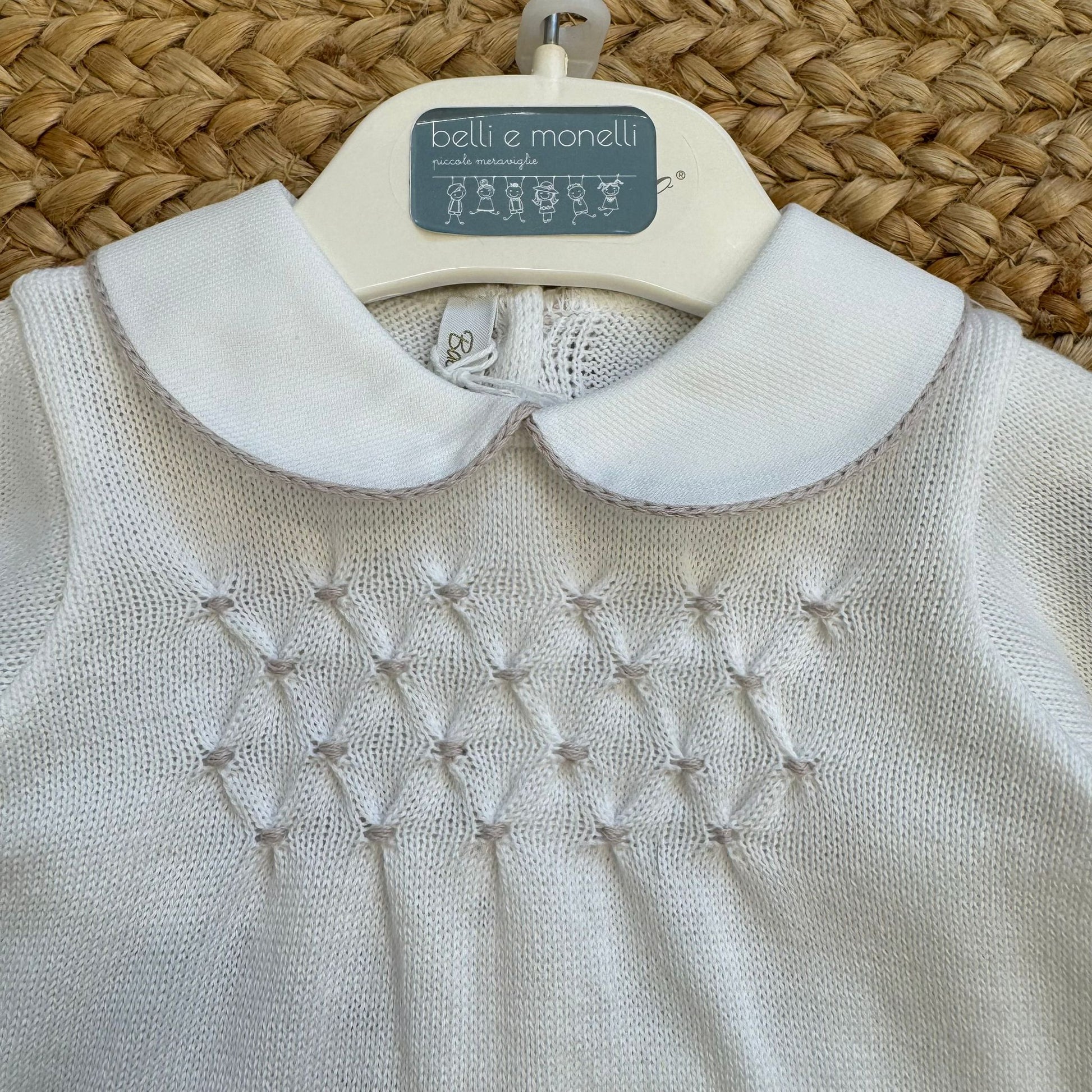 Dettaglio lavorazione a punto nodino sulla maglia della tutina neonato unisex in cotone panna