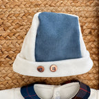 Dettaglio tutina neonato in ciniglia panna con inserto tartan e vellutino azzurro