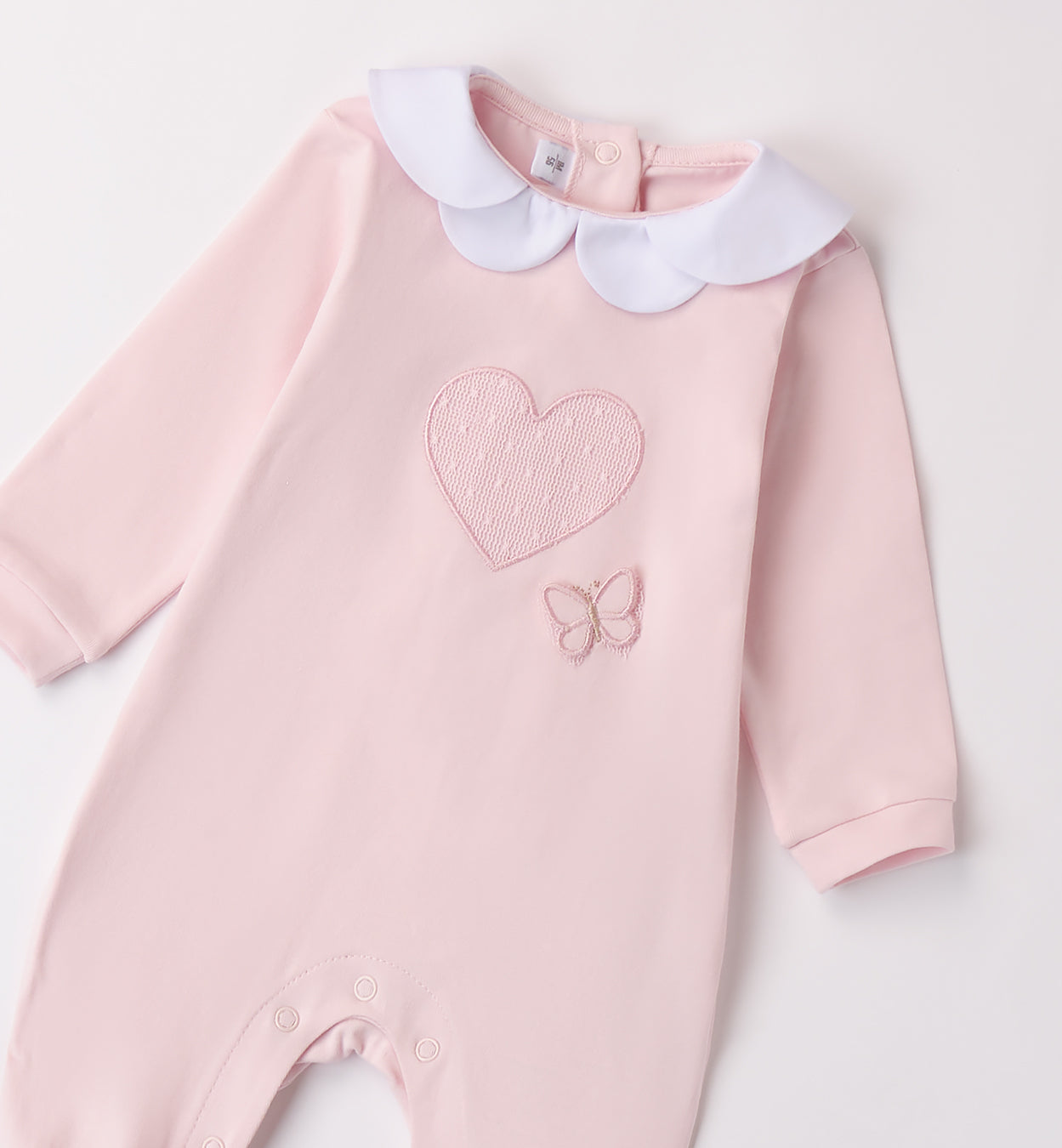 Delicata tutina in cotone rosa con ricamo cuore e farfalla, perfetta per i primi giorni della tua bambina. Realizzata in 100% cotone Made in Italy, garantisce morbidezza e comfort sulla pelle delicata del neonato. Il colletto in piqué bianco aggiunge un tocco di raffinatezza, mentre la chiusura con bottoncini a pressione sul retro e sul cavallo facilita il cambio.

Ideale per l’uscita clinica, le prime coccole a casa e le occasioni speciali.