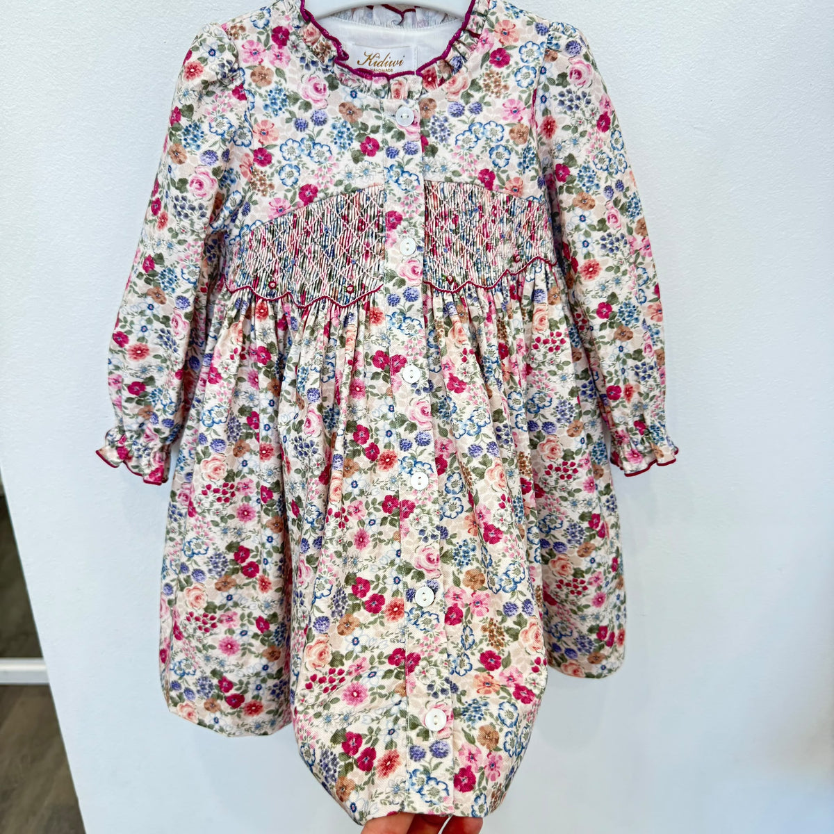 Abito bambina floreale in cotone con punto smock, colletto arricciato e dettagli bordeaux Kidivi.