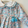 Abitino bimba floreale 100% cotone con colletto bianco e pon pon azzurri.