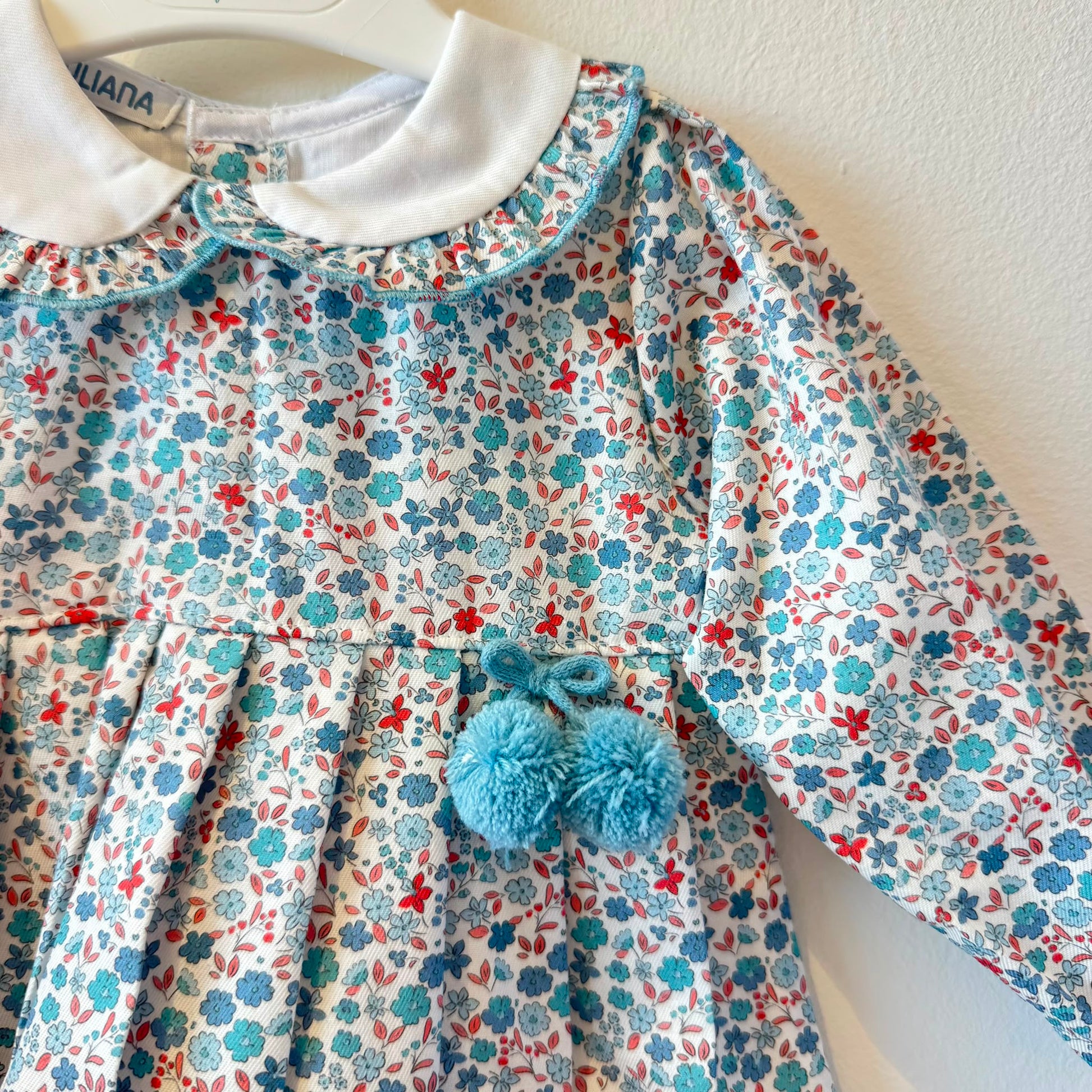 Abitino bimba floreale 100% cotone con colletto bianco e pon pon azzurri.