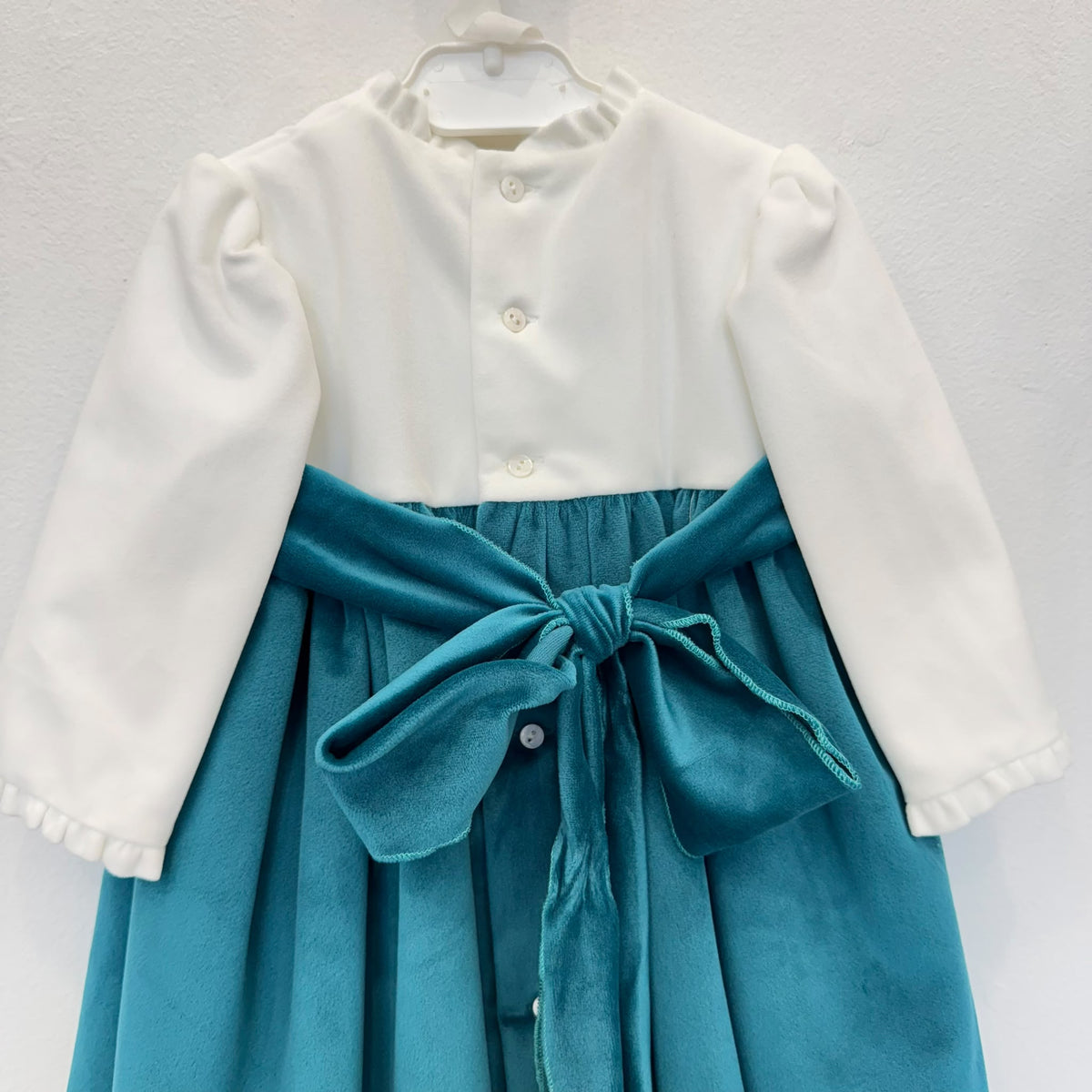 Dettaglio abito elegante bimba in velluto ottanio con corpetto panna e fiori rosa