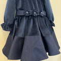 Abito elegante bimba blu in velluto con colletto arrotondato, maniche lunghe e tre fiori decorativi sul punto vita.